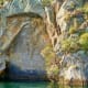 Ancient Maori rock carving (pataka) on cliff face above turquoise water, Toutai New Zealand